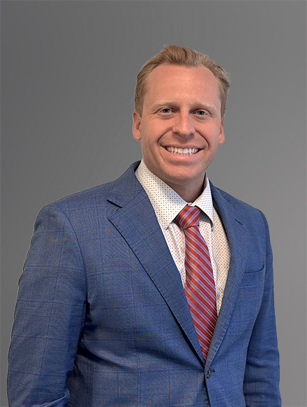 Attorney Nicholas T. Smith in a Blue Jacket with a White Patterned Shirt and Red Tie with Diagonal Gold Stripes