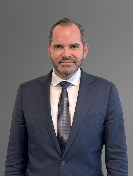 Attorney Frank R. Pumarejo-Martin in a Navy Suit with a White Shirt and Gray Tie